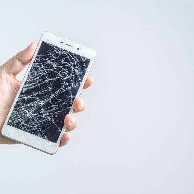 A person holding an iphone with broken screen.
